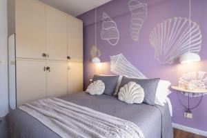 a bedroom with purple walls and a bed with pillows at Conchiglia design vista mare/spiaggia+parking in Diano Marina
