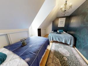 a attic bedroom with two beds and a chandelier at Moulin Harry 21 pers : 10 min Viaduc de la Souleuvre in Le Tourneur