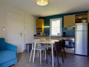 a kitchen with a table and chairs and a refrigerator at Grande maison adaptée in Figeac