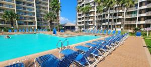 Una piscina con sillas azules frente a un edificio. en Saida Royale 9039, en South Padre Island