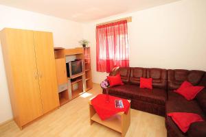 sala de estar con sofá marrón y almohadas rojas en Apartment Mile, en Zadar