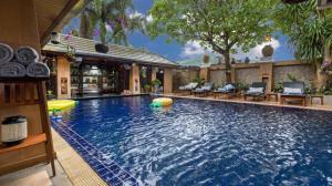 a large swimming pool with chairs and a house at The Nai Harn Collective in Rawai Beach