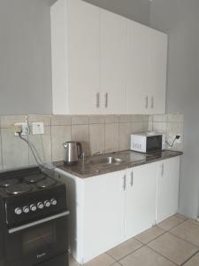 a kitchen with white cabinets and a sink and a stove at Entire rental unit in Pretoria