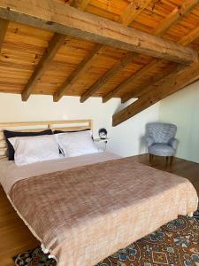 a bedroom with a large bed and a chair at CASAS LENTAS Slow Living-Óbidos in Sobral