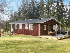 a small red shed with a porch and a table at 6 person holiday home in Sävsjö in Nykulla