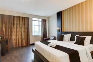 a hotel room with two beds and a desk at Collection O Stefani City Hotel in Pekanbaru