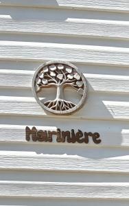 Un cartel en un edificio blanco con un árbol encima. en Marinière, en Sainte-Croix-du-Verdon