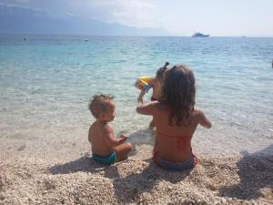 two children playing on the beach in the water at Apartment Tara in Sumartin