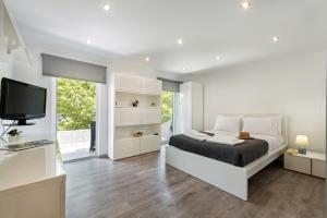 a white bedroom with a bed and a television at Casa dos Quatro in Faro