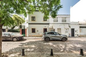 two cars parked in a parking lot in front of a building at Casa dos Quatro in Faro