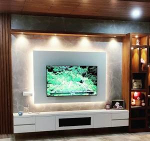 a living room with a tv on a wall at Samsthaanam - Luxury 3BHK Villa with Pool in Udupi in Kalyānpur
