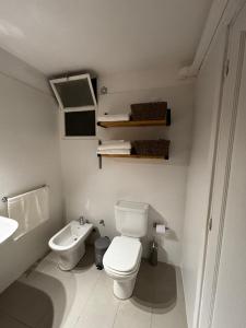 a white bathroom with a toilet and a sink at Frente al mar in Montevideo +9 photos