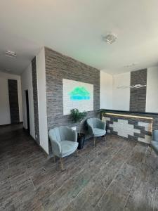 a lobby with two chairs and a brick wall at Pensiunea Ciucar Dubova in Dubova