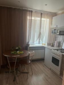 a kitchen with a table with chairs and a stove at Apartment on Artyleriiska 2 with River View in Mykolaiv +3 photos