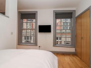- une chambre avec deux fenêtres, un lit et une télévision dans l'établissement Apartment 9, à York