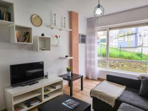 a living room with a couch and a tv and a window at Casa Taro San Vicente de la Barquera in San Vicente de la Barquera +26 photos