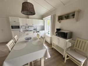 a kitchen with a white table and chairs and a microwave at Myfa Beachcottage Zeewind II 270 in Bredene