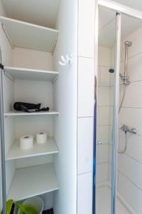 a bathroom with white shelves and a shower at AugsburgLiving - Business- und Ferienapartments in Augsburg