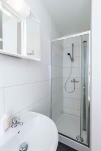 a white bathroom with a shower and a sink at AugsburgLiving - Business- und Ferienapartments in Augsburg +63 photos
