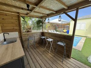 a patio with a bar and chairs on a deck at Anaïs Pool in Saint-Joseph