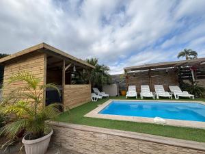 a backyard with a pool and chairs and a house at Anaïs Pool in Saint-Joseph