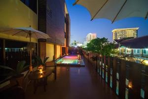a balcony with tables and an umbrella and a pool at CM Night Bazaar Boutique Hotel - โรงแรม ซี เอ็ม ไนท์บาซาร์ บูทีค in Chiang Mai