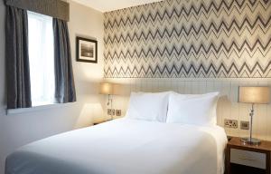 a bedroom with a large white bed and a window at Fishermans Tavern in Dundee