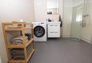 a white bathroom with a washing machine and a shower at Moderne leilighet sentralt på Tromsøya in Tromsø