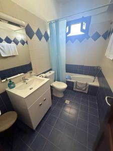 a bathroom with a sink and a toilet and a tub at Familyhouse apartments Arkasa in Arkasa