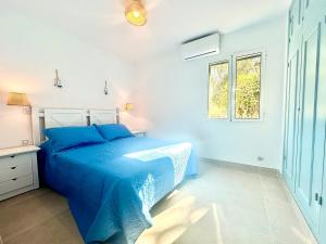 a bedroom with a blue bed and a window at Addaia in Port d'Addaia +19 photos