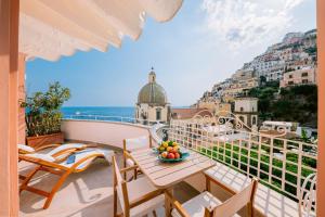 a balcony with a table and chairs and a view of the city at Dimora Donna Teresa in Positano