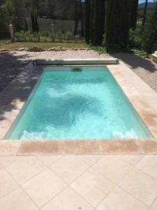 een klein zwembad met blauw water op een patio bij Le Putt-Tee Bastidon in Nans-les-Pins