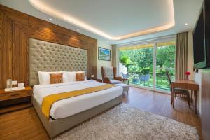 a bedroom with a bed and a desk and a window at Snow Valley Resorts & Spa Manali in Manāli