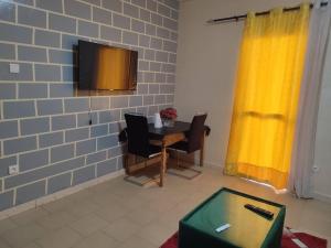 a room with a table and a tv on a brick wall at Studio Terminus 61 in Keur Massar