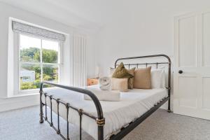 a white bedroom with a metal bed with pillows at Coastal Home in Mumbles with Garden & WiFi in Swansea