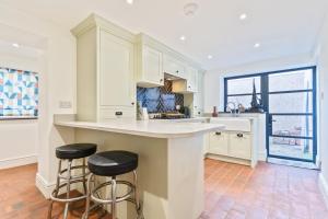 a kitchen with white cabinets and two bar stools at Coastal Home in Mumbles with Garden & WiFi in Swansea