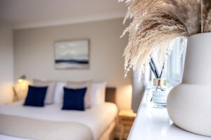 a room with a couch with blue pillows and a vase at The Inn For All Seasons in Redruth