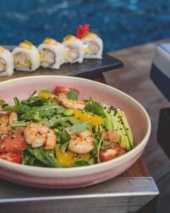 a bowl of shrimp and vegetables on a table with sushi at Alliance Palace In Batumi in Batumi