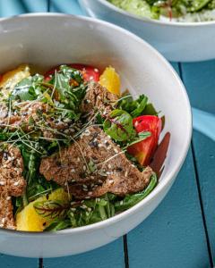 a bowl of salad with meat and vegetables on a table at Alliance Palace In Batumi in Batumi +1 photo