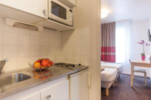 a kitchen with a sink and a bowl of fruit on the counter at Appart'City Classic Lyon Part Dieu Garibaldi in Lyon