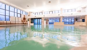 a swimming pool with water in a building at Thalazur Ouistreham - Hôtel & Spa in Ouistreham +17 photos