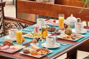 a table topped with plates of breakfast foods and orange juice at Hôtel Marso in Amnéville