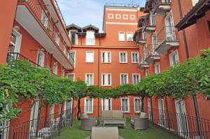 a courtyard of an apartment building with chairs and plants at Cavour 30TRE - Hotel Moderno in Stresa
