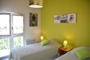 een groene slaapkamer met 2 bedden en een raam bij Les Floralies in La Tranche-sur-Mer +16 foto's