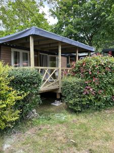 a small house with a black roof and some bushes at Camping Le Roc in Vairé