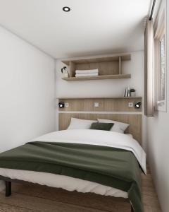 a bedroom with a green and white bed and shelves at Camping Le Roc in Vairé