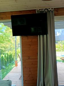 Un televisor de pantalla plana en una pared en una habitación con ventana. en Wisla66 Domki nad Wisłą Piotrawin, 
