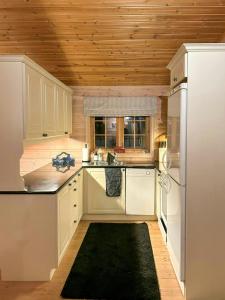 a kitchen with white appliances and a wooden ceiling at Mountain Cabin With Ski Tracks Nearby in Øyer +8 photos