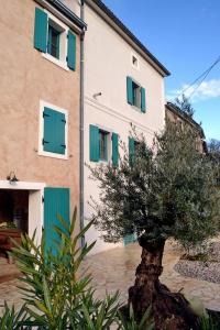 a building with green shutters and a tree in front of it at Holiday home Olea in Malinska