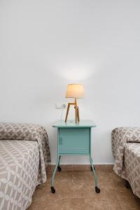 a blue table with a lamp on it next to two beds at Apartamentos Madrid in Torrevieja
